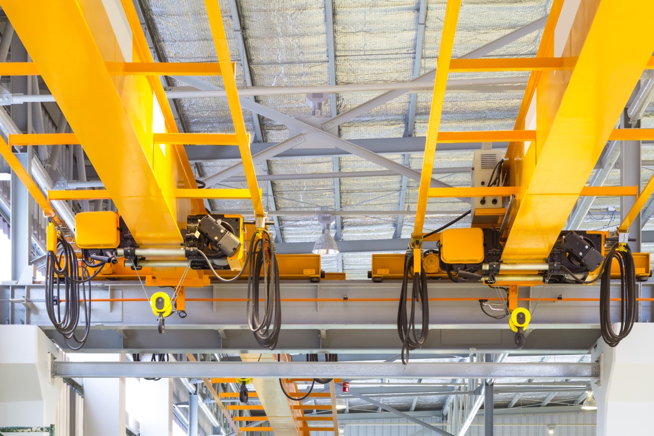 Overhead crane and hook inside factory building for lifting work.