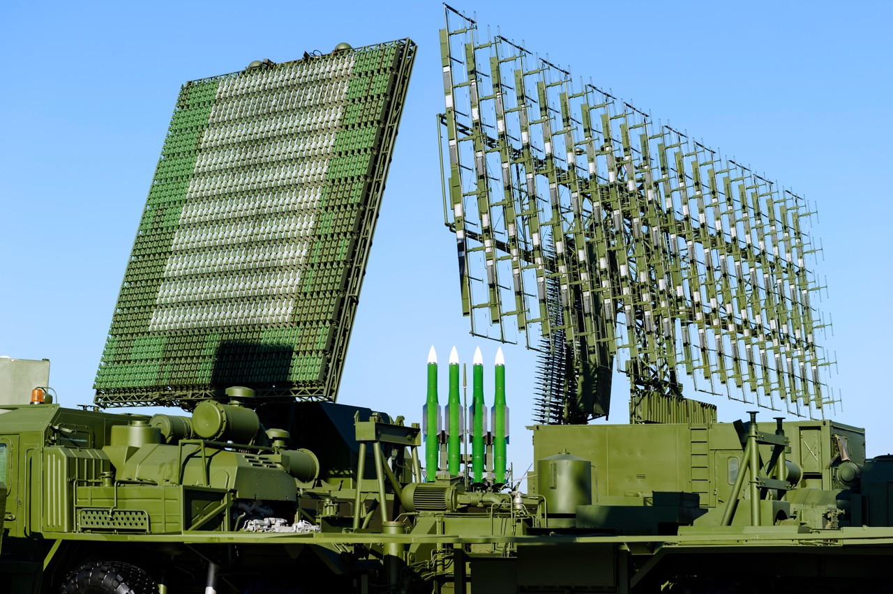 Air defense radars of military mobile antiaircraft systems in green color and ballistic rocket launcher with four cruise missiles in centre of frame, modern army industry